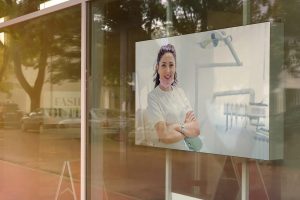 empty white poster frame on glass of showcase window of shopping mall fashion outlet centre mock-up
